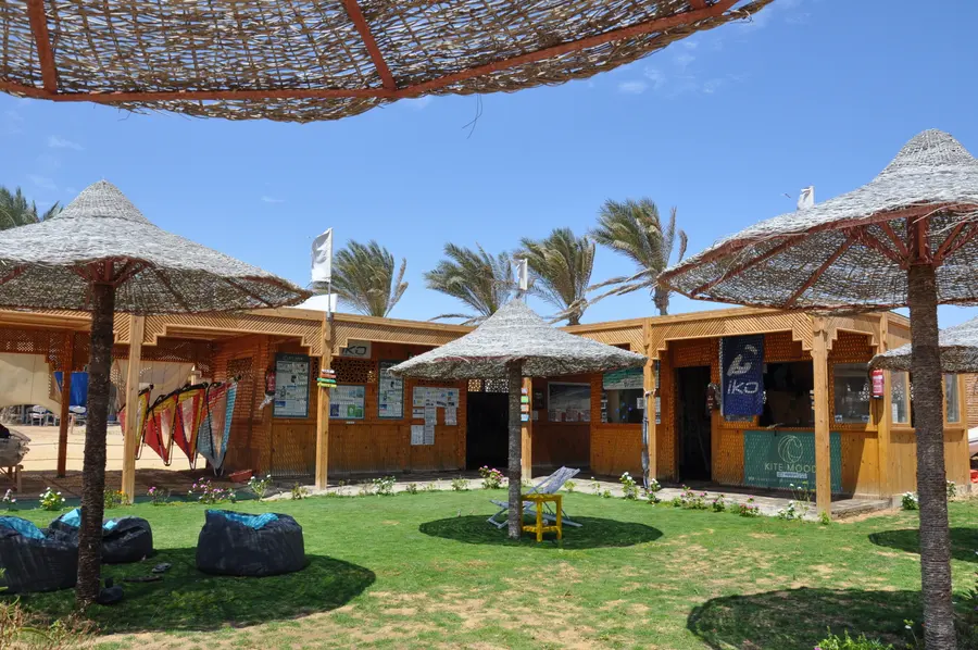 Wooden KiteMood kite centre with thatched parasols, a lawn with bean bags and an IKO banner