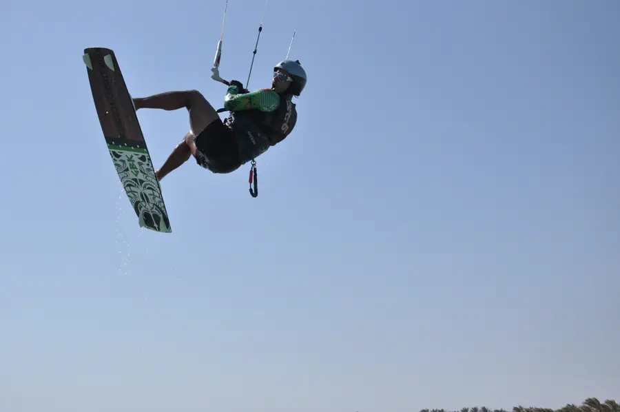 Kitesurfer in mid-air with the board against a clear blue sky